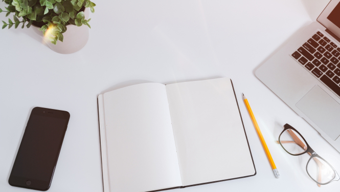 uz galda dators, bloknots, zīmulis un telefons